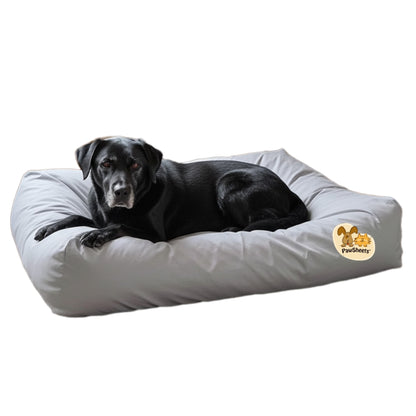 Black labrador retriever resting on a bolster style dog bed covered with a gray PawSheets dog bed cover