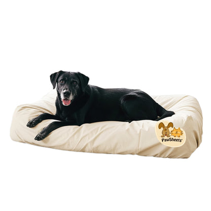 Black labrador retriever resting on a bolster style dog bed covered with an off white PawSheets dog bed cover