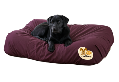 Dog on a large bolster dog bed with a burgundy PawSheets dog bed cover