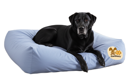 Black dog lies on a large, cushioned rectangular dog bed with a light blue PawSheets dog bed cover.
